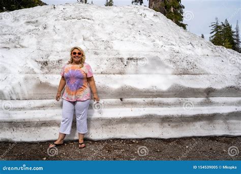 Cute Blonde Tourist Woman Poses And Stands Next To A Large Mound Of Plowed Snow In Lassen