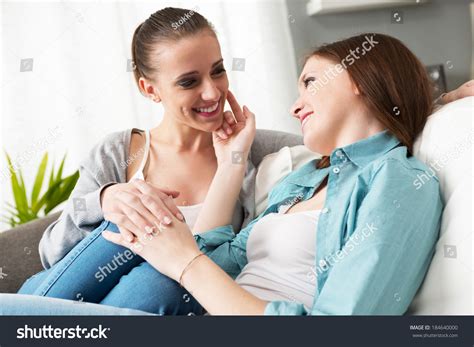 Loving Lesbian Couple Flirting And Holding Hands On The Sofa At Home Stock Photo