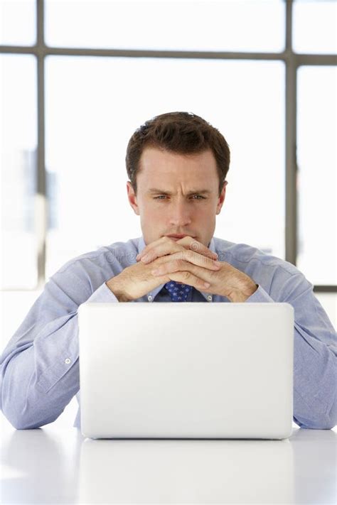 Бизнесмен сидя на столе в офисе используя компьтер-книжку Стоковое Фото ...