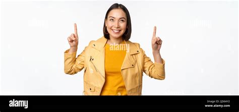 Image Of Smiling Asian Brunette Woman Pointing Fingers Up Showing