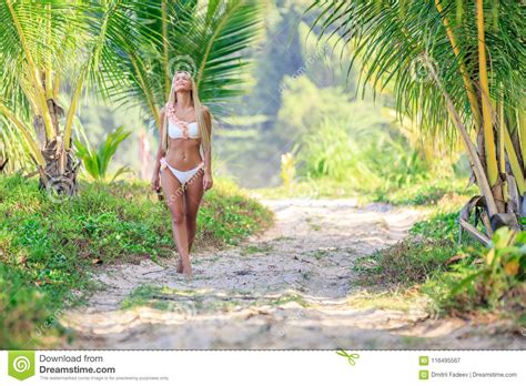 Mujer En El Bikini Blanco Que Camina Entre Las Palmeras En El Tropical