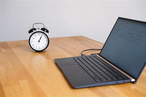 Premium Photo Alarm Clock And Laptop On The Wooden Desk