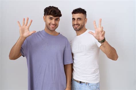 Homosexual Gay Couple Standing Over White Background Showing And Pointing Up With Fingers Number