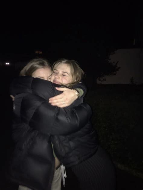 Two Women Hugging Each Other Outside At Night