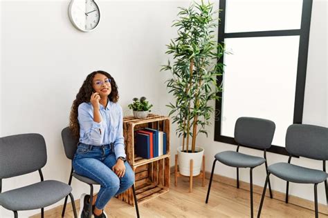 Joven Latina Hablando En El Smartphone Sentado En La Silla En La Sala De Espera Imagen De