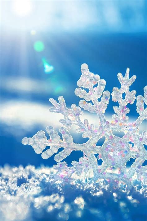 a snowflake that is sitting in the snow with sun shining through it's lens