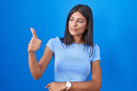 Jovencita De Brunette Parada Sobre Fondo Azul Con Aspecto De Orgullosa Sonrisa Haciendo Gestos