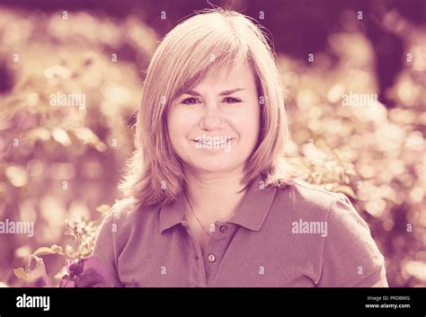 Closeup Portrait Of Glad Blond Mature Woman Enjoying Her Time In Garden