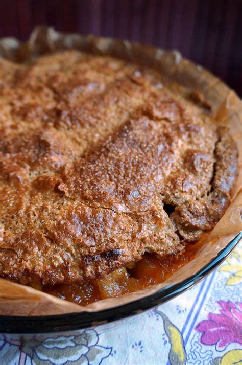 A Pie Sitting On Top Of A Wooden Plate Next To A Flowery Table Cloth