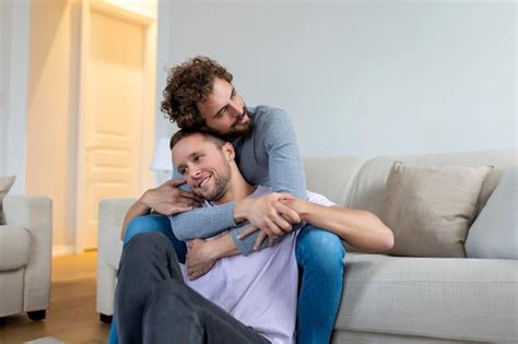 Lindo casal gay beijando enquanto está sentado em sua sala de estar em casa dois românticos