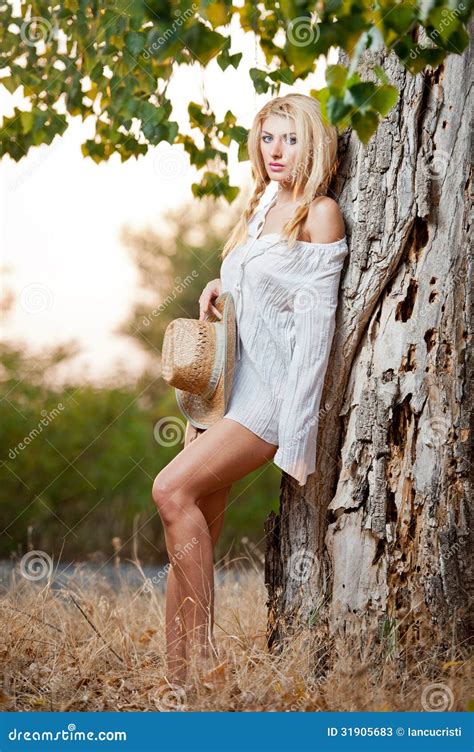 Zeer Leuke Blonde Vrouwenzitting Onderaan Openlucht Met Een Hoed Dichtbij Een Boom Stock