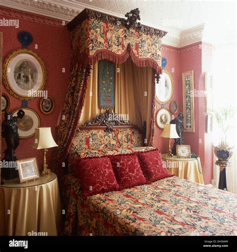 Rich tapestry drapes on half tester bed with red velvet cushions in red