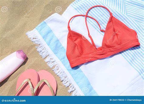 Toalla Rayada Con Una Botella Superior De Bikini De Protector Solar Y Chanclas En La Playa De