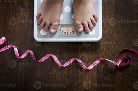 Top View Of Feet On Weight Scale With Wooden Floor And Measuring Tape