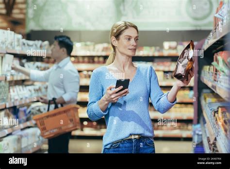 Eine Sch Ne Junge Blonde Frau Steht In Einem Supermarkt Sie H Lt Ein Telefon Und Eine Packung