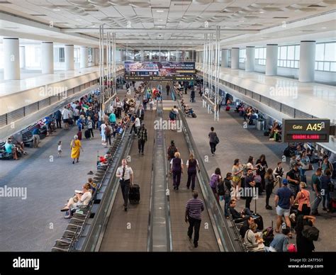 Pilots, workers, and passengers in a busy airport terminal with moving ...