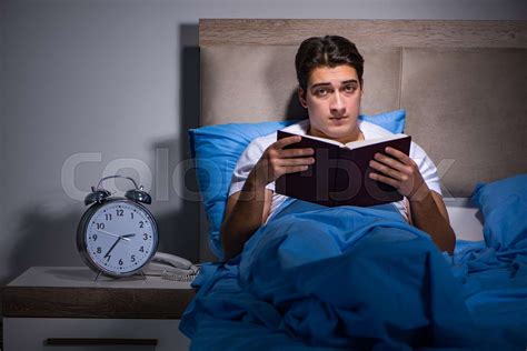 Young man reading book in bed | Stock image | Colourbox