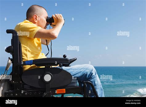 Disabled Man With Binocular Sitting On The Wheelchair Sea On The