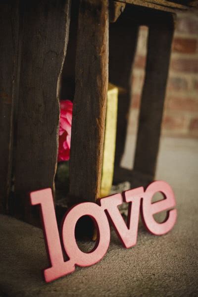 The Word Love Spelled Out In Front Of A Wooden Chair With Pink Flowers