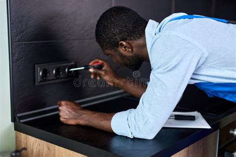 Confident African Electrician Repairs Installs Outlet In Kitchen Man