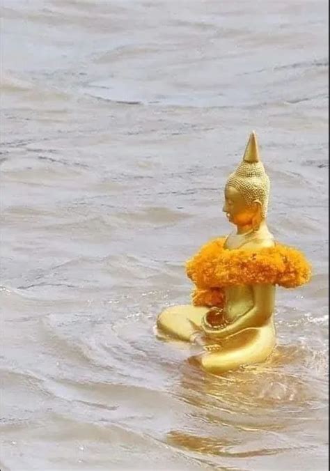 A Statue Is Floating In The Water With Flowers