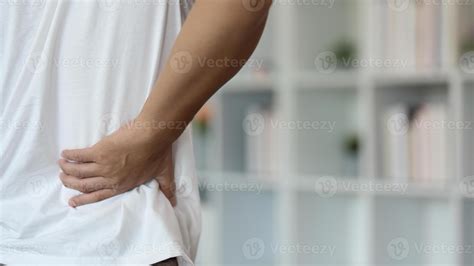 Back Pain Awareness. Young man holding lower back in discomfort while