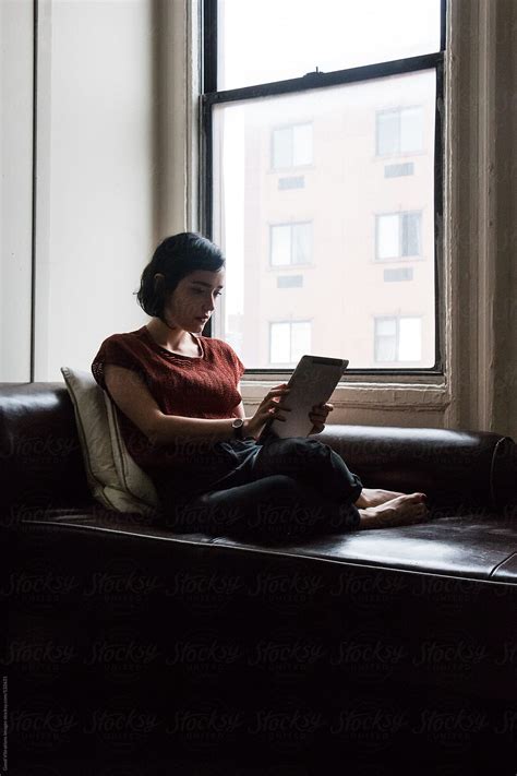 Brunette On The Sofa Reading A Digital Tablet By Stocksy Contributor Vero Stocksy
