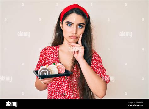 Brunette Teenager Girl Holding Cake Sweets Serious Face Thinking About