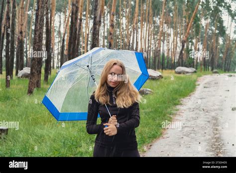 Blonde Girl Checking The Weather Under Transparent Umbrella Outside In Park Autumn Time Rainy