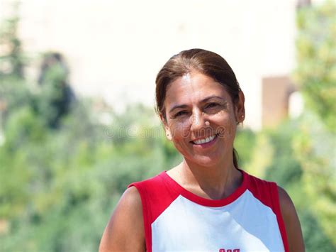 Portrait Of A Smiling Latina Woman With Her Hair Up And Wearing A Casual Red And White T Shirt