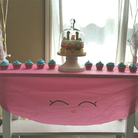 A Pink Table Topped With Lots Of Cupcakes And A Cake Covered In Icing