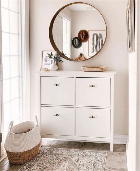 A White Dresser With A Round Mirror Above It And A Basket On The Floor