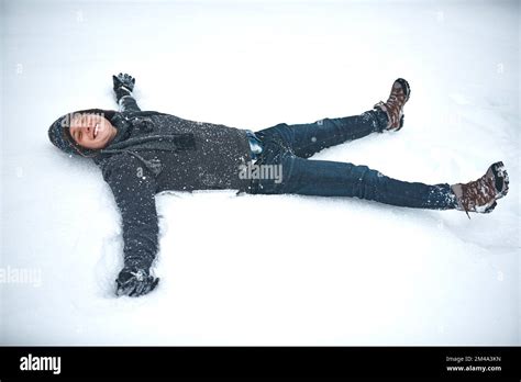 If life gives you snow, make snow angels. a young man lying in the snow ...