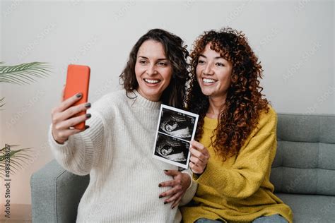LGBT Lesbian Couple Holding Ultrasound Photo Scan On Video Call Of Growing Baby In Pregnancy