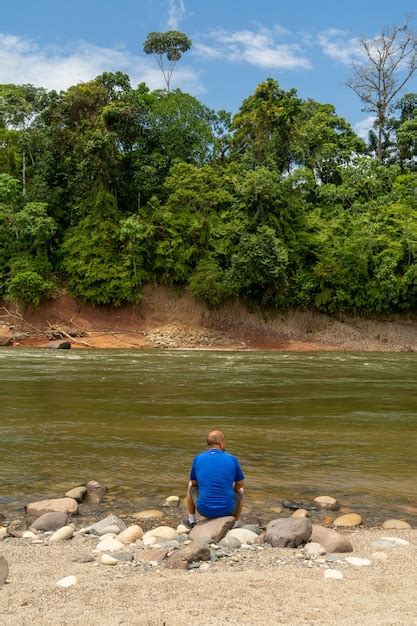 Un Solo Hombre Sentado A La Orilla Del Río En La Selva Amazónica