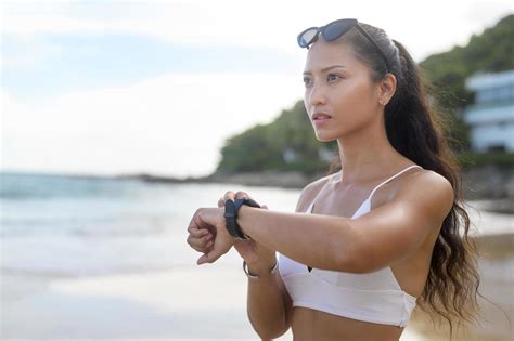 jeune belle femme en bikini se détendre et utiliser une smartwatch sur