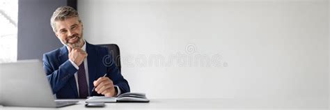 Successful Mature Businessman Sitting At Desk With Laptop In Office