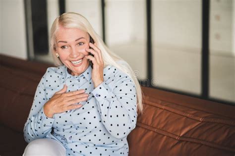 Blonde Mature Woman Talking On The Phone While Sitting On The Sofa Stock Image Image Of Blonde