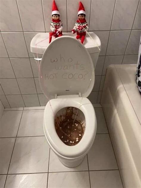 Two Elfs Sitting On Top Of A White Toilet In A Bathroom With Tile Flooring