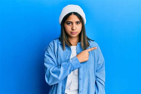 Joven Latina Con Una Linda Gorra De Lana Apuntando Con El Dedo De La Mano Hacia El Lado