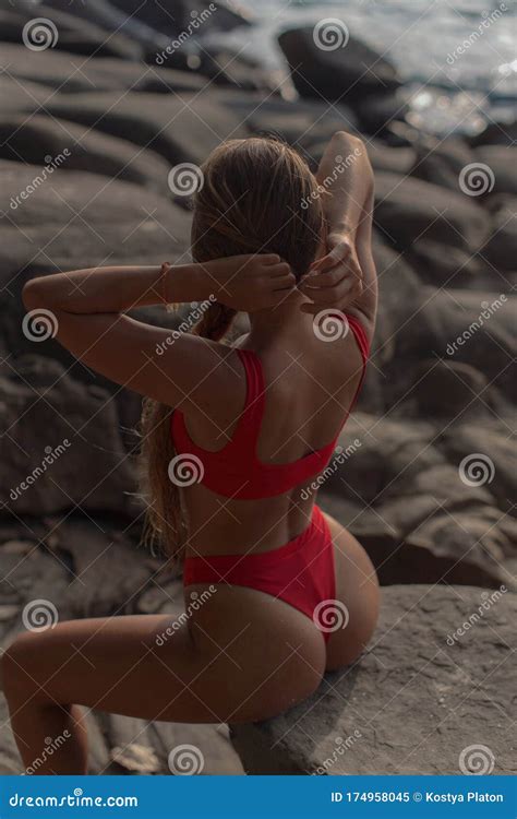 Body Tanned Brunette In Red Bikini Posing With Her Back To Camera Among