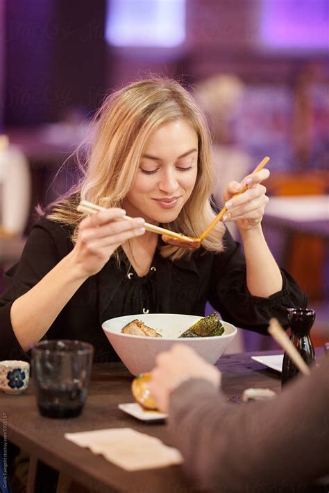 Content Woman Eating Dinner With Chopsticks By Stocksy Contributor
