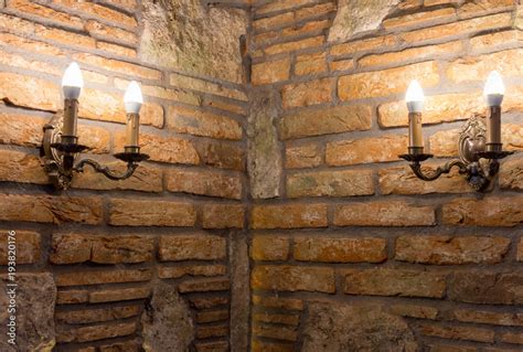 Two Candlesticks With Lamps In Corner Of Brick Wall In Ancient Building