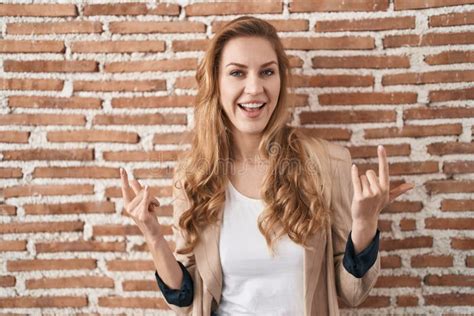 Belle Femme Blonde Debout Sur Des Briques Mur Crier Avec Une Expression Folle Faire Rock Symbole