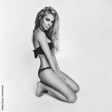 Elegant Sexy Woman In The Bikini On The Sun Tanned Slim And Shapely Body Is Posing On White