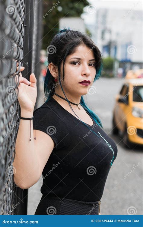 Bella Latina En La Calle Inclinada Sobre Una Malla De Alambre En Un Armario Foto De Archivo