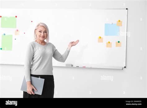 Mature Teacher With Notebook Near Whiteboard In Classroom Space For Text Stock Photo Alamy