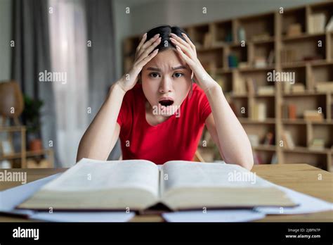 Sad Shocked Teen Chinese Lady Student With Open Mouth Study At Table