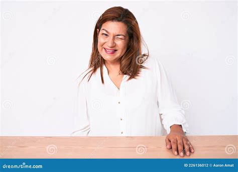 Brunette De Mediana Edad Mujer De Negocios Hispana Con Camisa Blanca Casual Sentada En La Mesa