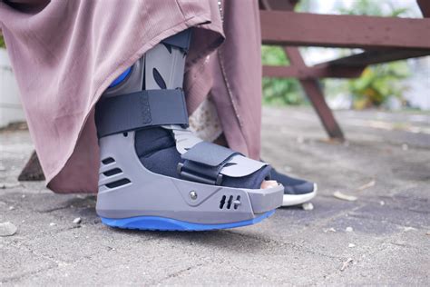 women broken feet with a grey plastic boot ankle brace injury